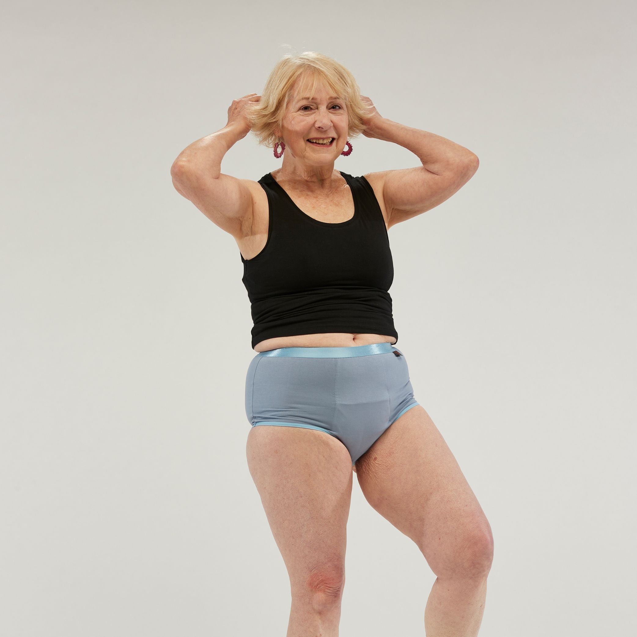 Confident older woman wearing StayDry full brief underwear in blue, designed for comfort, waterproof protection and incontinence support, ensuring style and security for everyday wear.