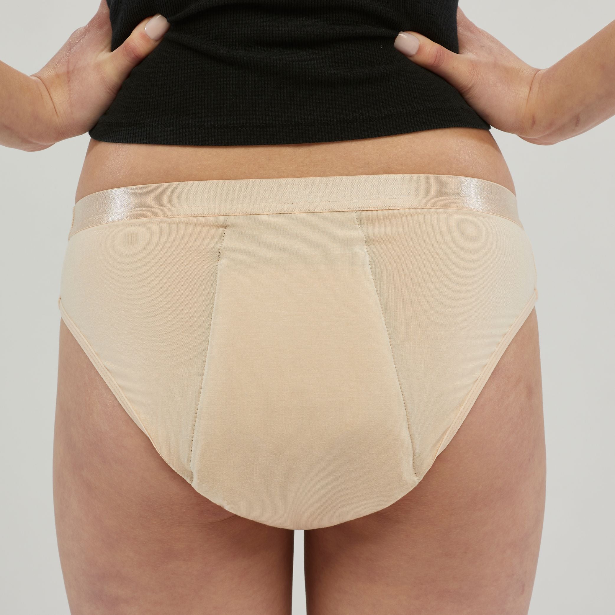 Back view of beige waterproof incontinence hipster underwear for women, designed with a discreet leak-proof layer and a satin waistband for comfort and security.