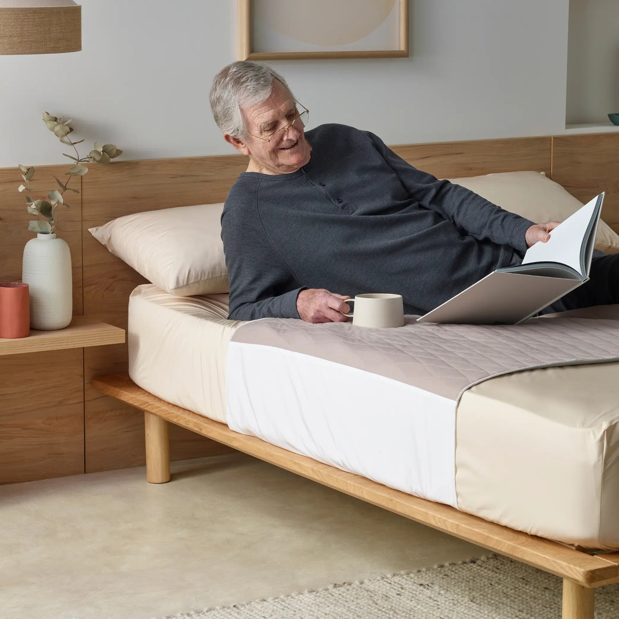 Elderly man relaxing on a bed with a quilted waterproof bed pad, some call it kylie bed pad in clay colour. Designed for incontinence protection, this absorbent, breathable, and washable bed pad keeps bedding dry and comfortable.
