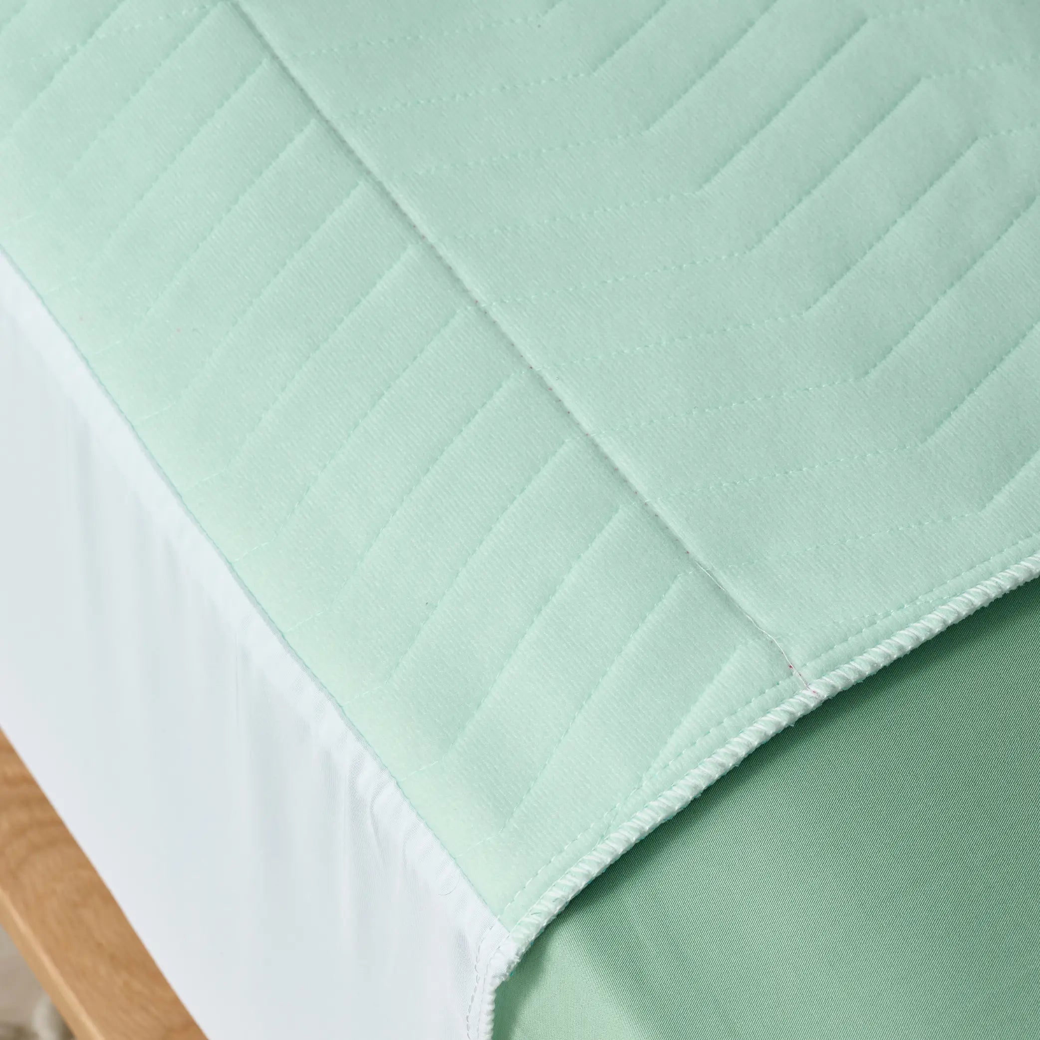 Close-up of the Boss Waterproof Bed Pad, customers also call it Kylie bed bad in sage green, showing its soft, quilted texture and high-absorbency layers. Designed for incontinence protection, this reusable and washable bed pad ensures mattress dryness while providing breathable comfort.