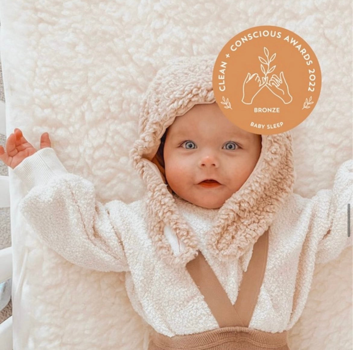 Baby sleeping on waterproof mattress cot topper made from Australian lambswool. 