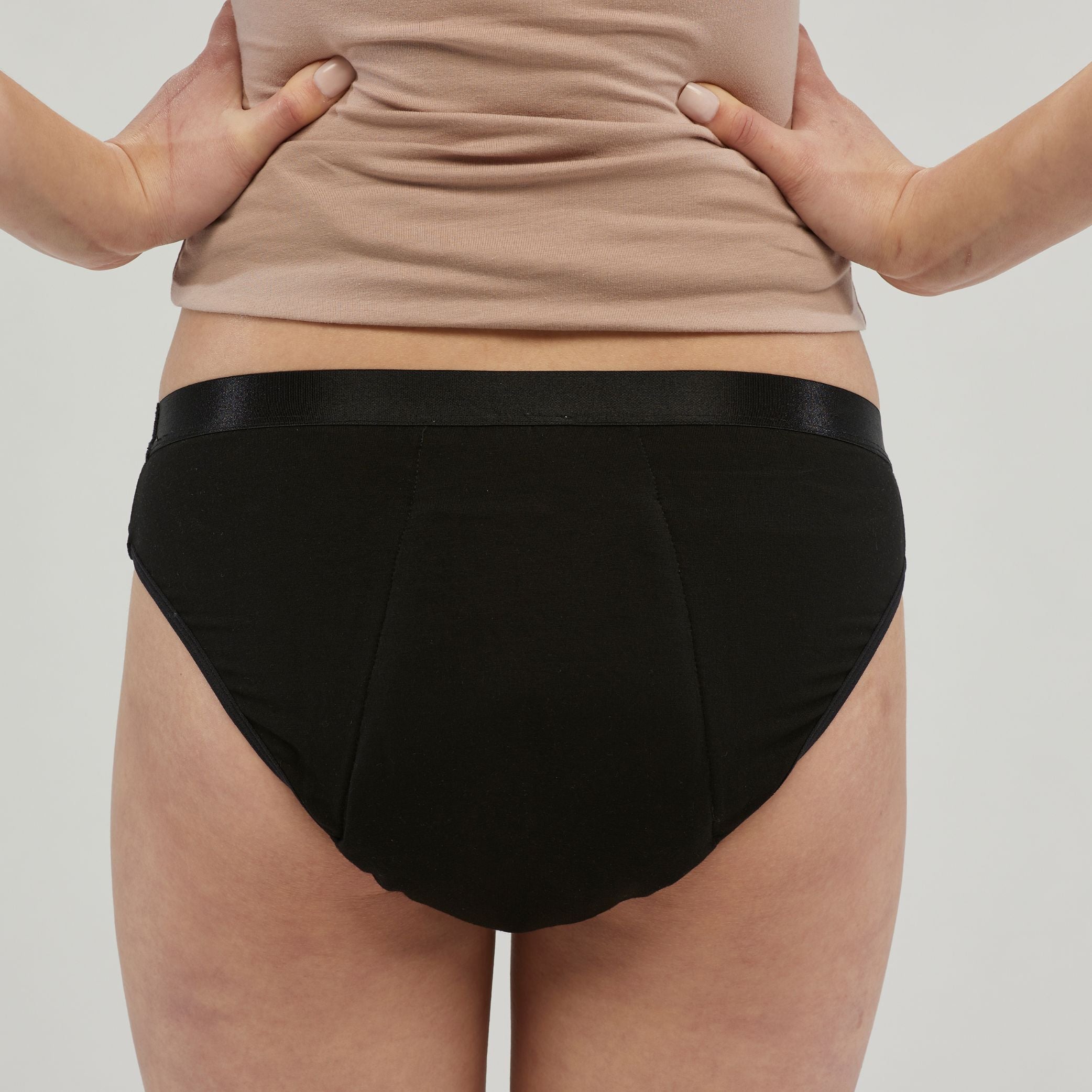 Back view of a woman wearing black waterproof incontinence hipster underwear, designed for leak-proof protection and discreet comfort. Features a soft, supportive waistband and a secure fit for everyday wear.