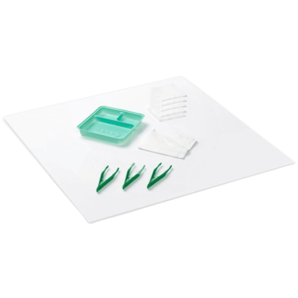 The contents of a sterile dressing pack laid out, featuring a white disposable underpad, a small green tray, three green plastic forceps, and several white gauze swabs and towels.